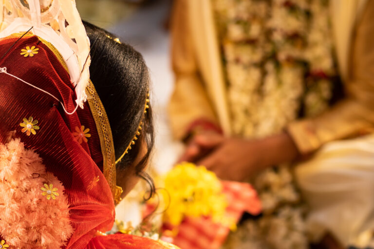 Hindu traditional marriage rites being performed with bride and groom sitting together in presence of priest. Bride in red saree. Symbolic photo of hindu religious culture of wedding ceremony.